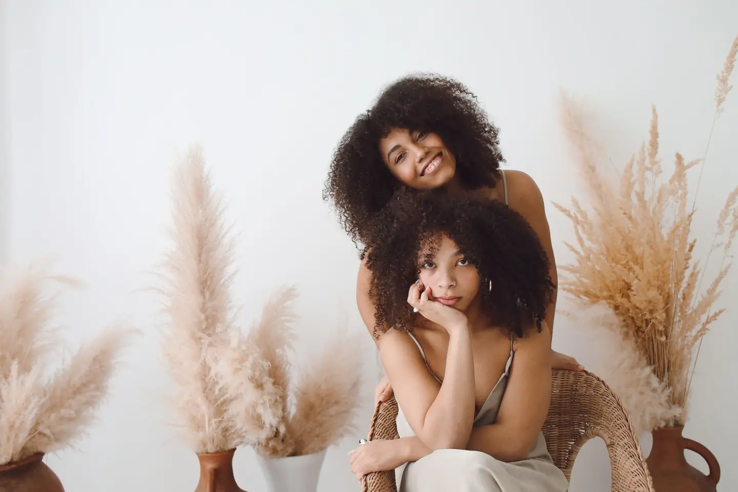 Twee vrouwen met krullend haar in een lichte studio met pampasgras