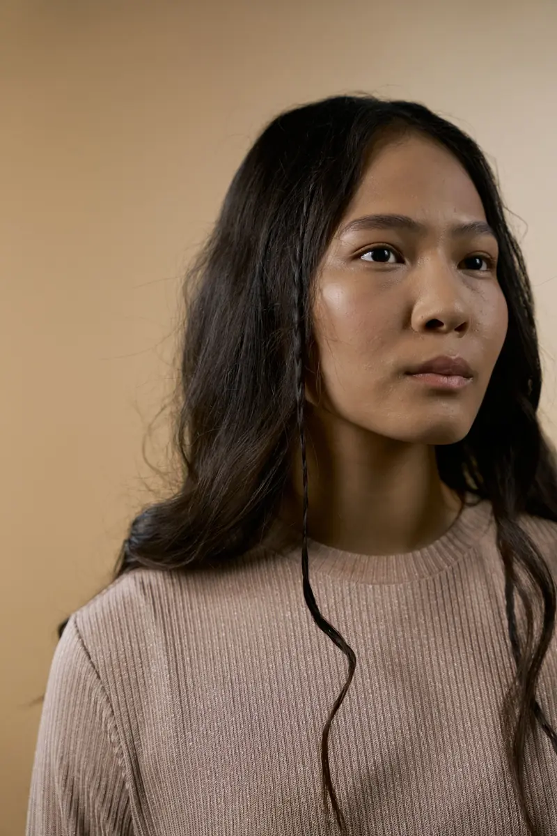 Vrouw met lang bruin haar in een beige trui